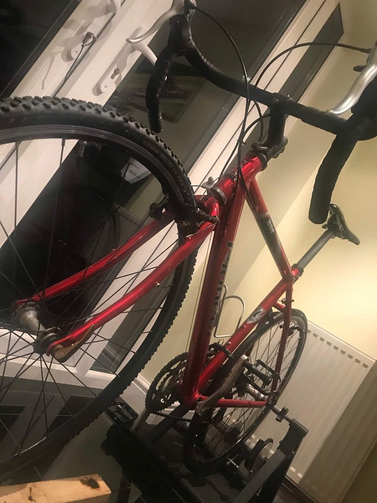 Red Raleigh road bike in a kitchen by patio doors with it's back wheel on a turbo trainer 