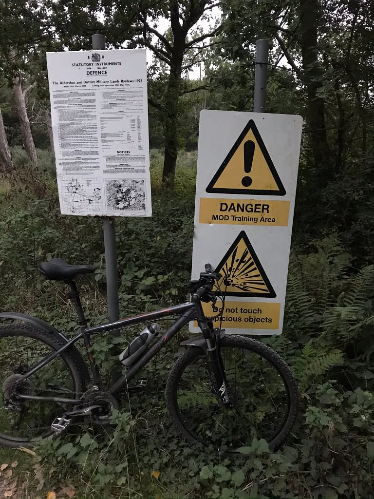 Mountain bike leaning against Ministry of Defence danger warning sign