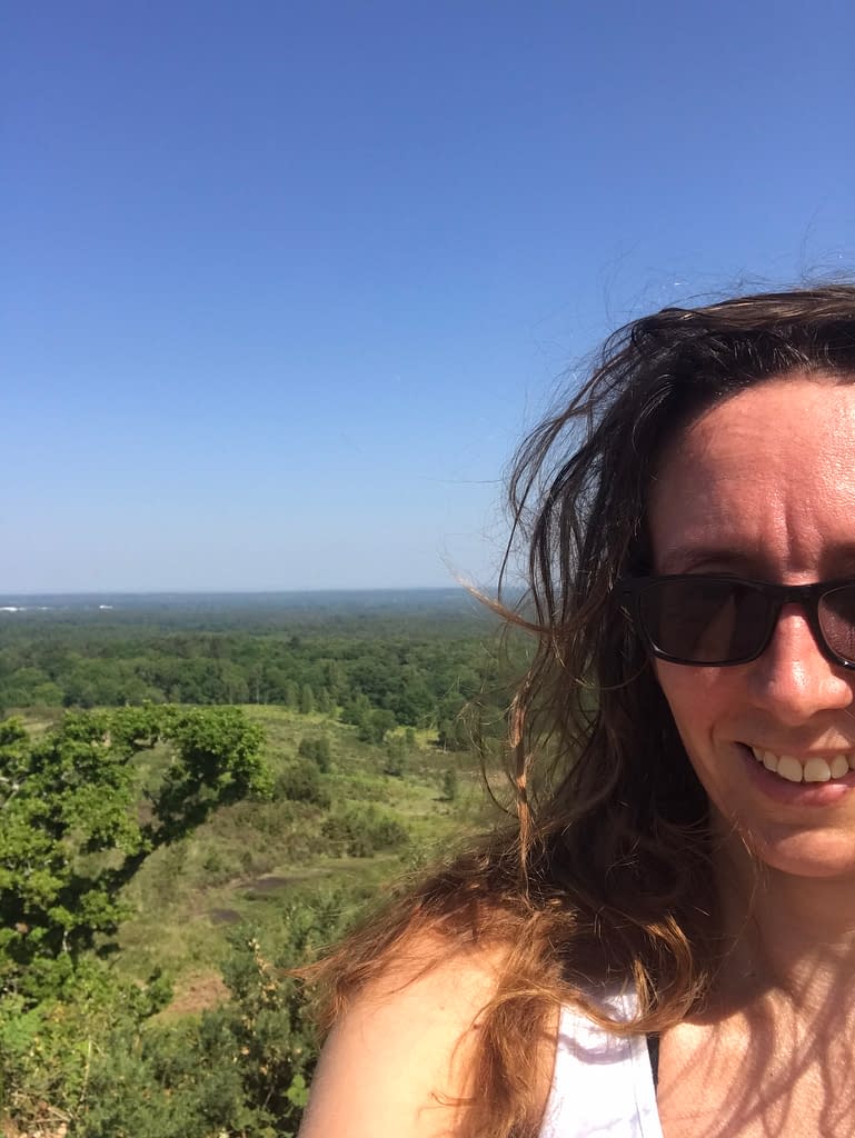 Woman smiling in front of the view over Hampshire countryside from Caesar's Camp viewpoint 