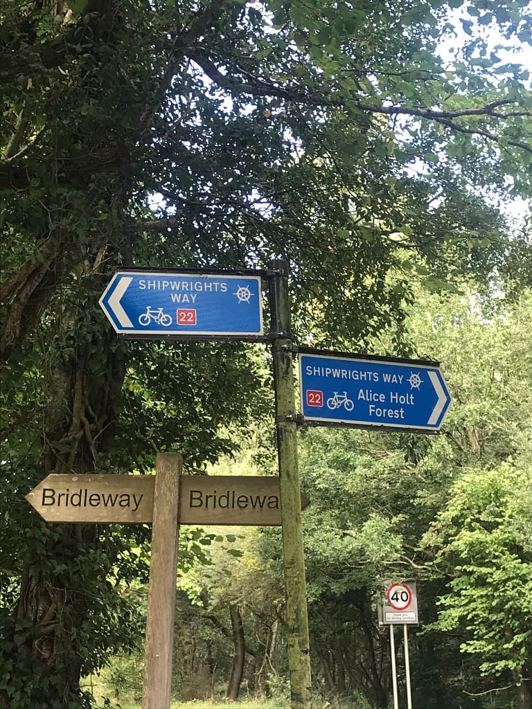 Bridleway signs underneath Shipwrights way cycle route 22 blue sign